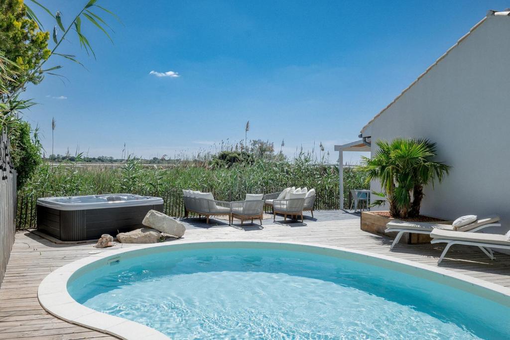a swimming pool on a patio with chairs and a table at La Perle Rose Villa Standing 5 étoiles avec piscine jacuzzi et superbe vue in Aigues-Mortes