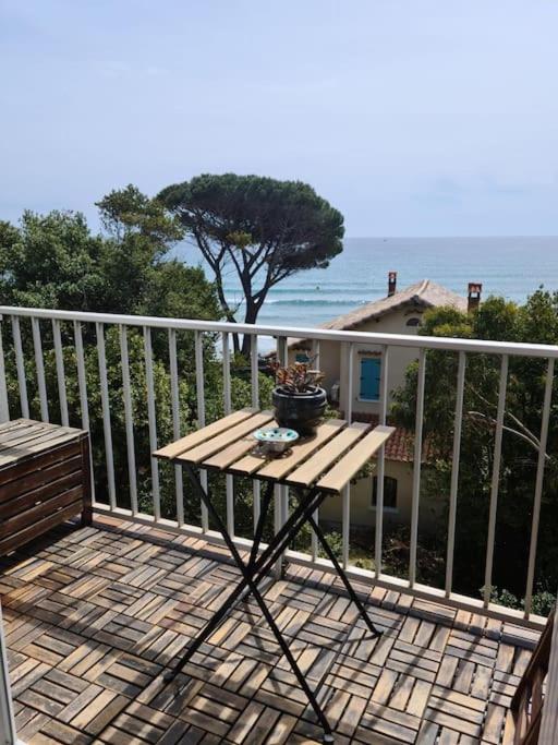 une table en bois sur un balcon avec vue sur l'océan dans l'établissement LES SABLETTES LES PIEDS dans L'EAU, à La Seyne-sur-Mer
