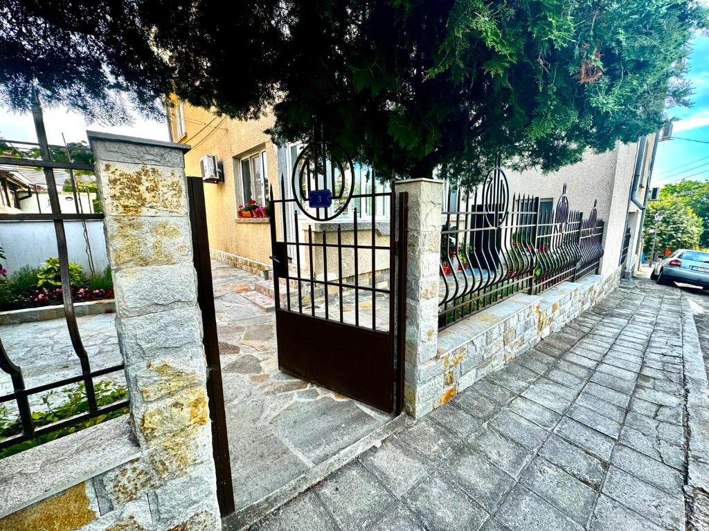 a gate with a tree in front of a house at Guestrooms Stoyanovi in Chernomorets
