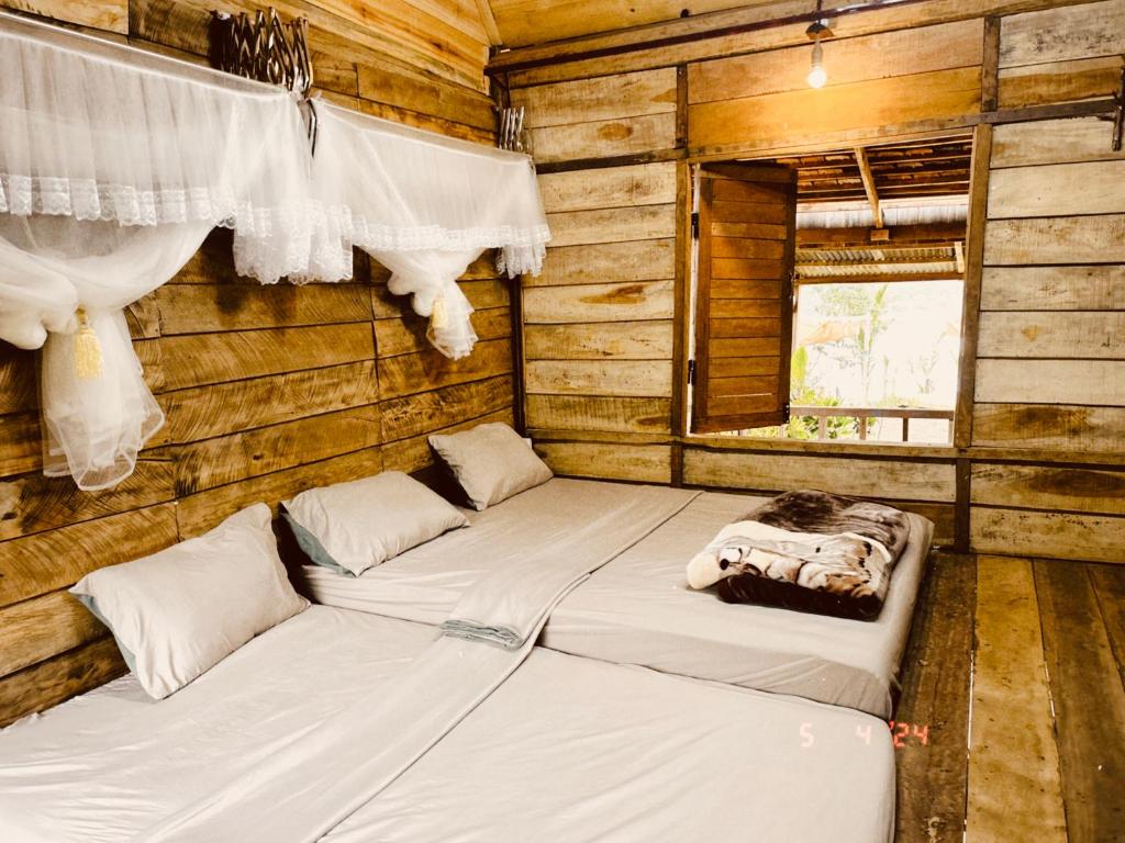 a room with two beds in a log cabin at An Homestay in Di Linh