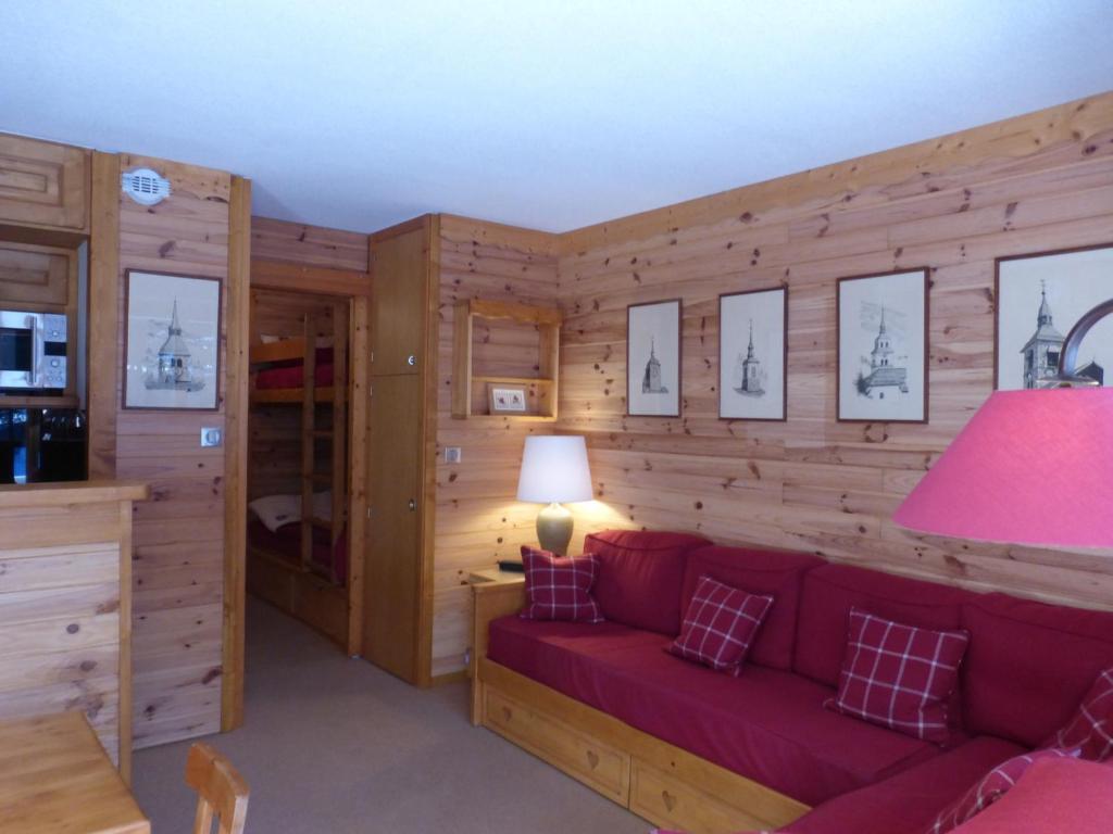- un salon avec un canapé rouge et des murs en bois dans l'établissement Studio confortable à Méribel Altiport, skis aux pieds, terrasse ensoleillée, proche forêt - FR-1-411-835, à Les Allues