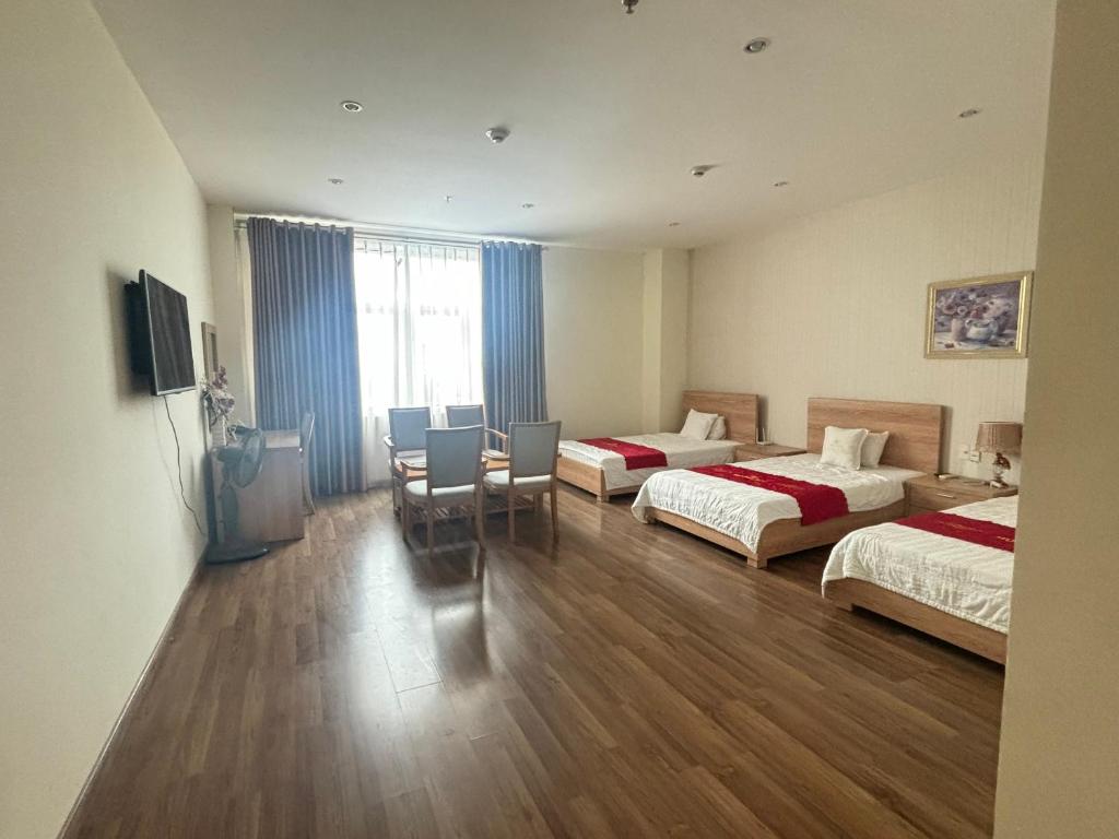 Cette chambre d'hôtel comprend deux lits, une table et des chaises. dans l'établissement Nhà Khách Hương Sen, à Hai Phong