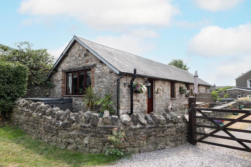 a stone cottage with a stone wall and a fence at Ivy Cottage in Pyle