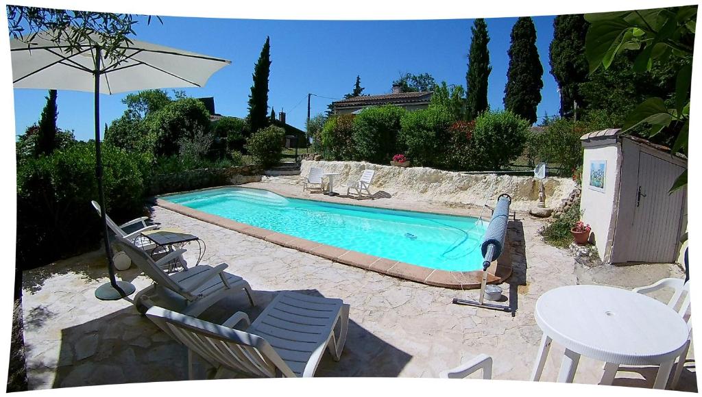 a swimming pool with chairs and a table and an umbrella at Le Moulin du Christ,villa avec piscine in Peyrefitte-sur-lʼHers