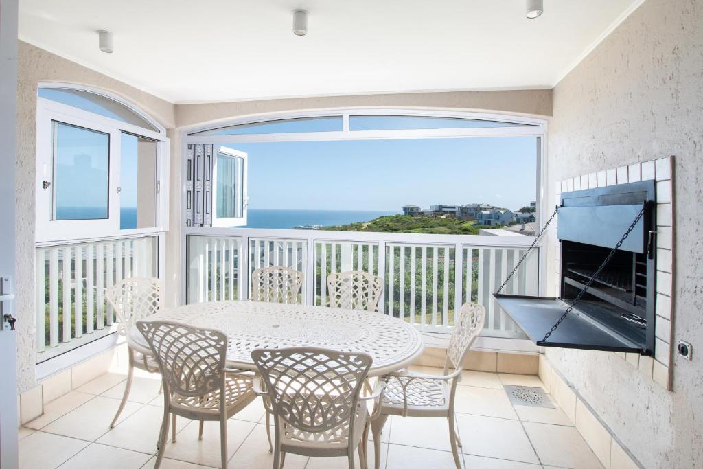 a dining room with a table and chairs on a balcony at Lifestyle Villa at Pinnacle in Mossel Bay