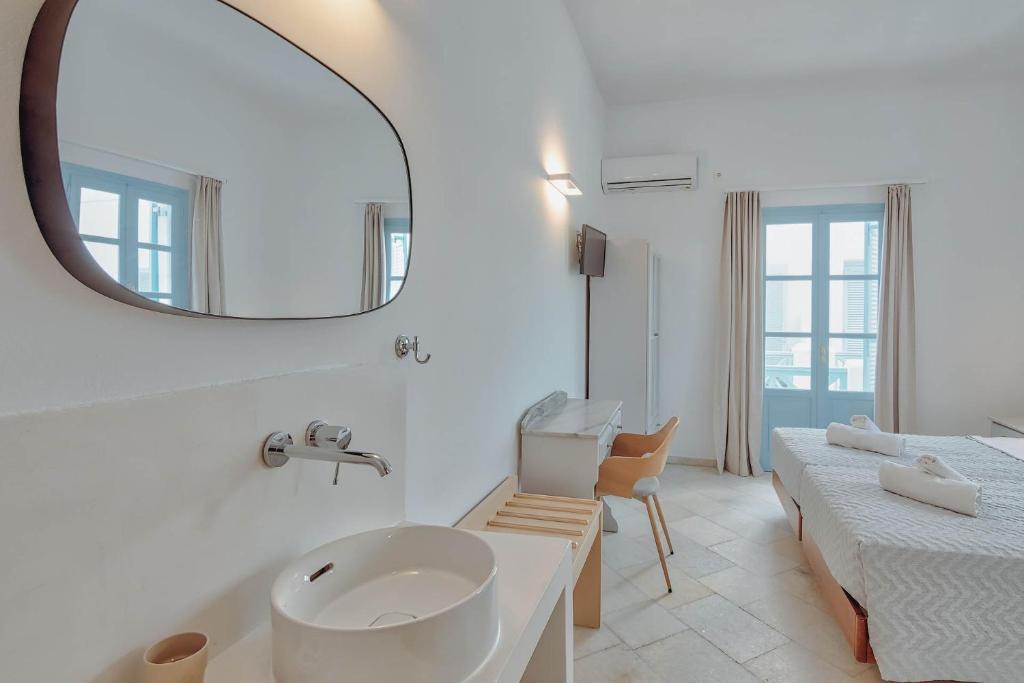 a white bathroom with a sink and a mirror at Hotel Mantalena in Antiparos Town