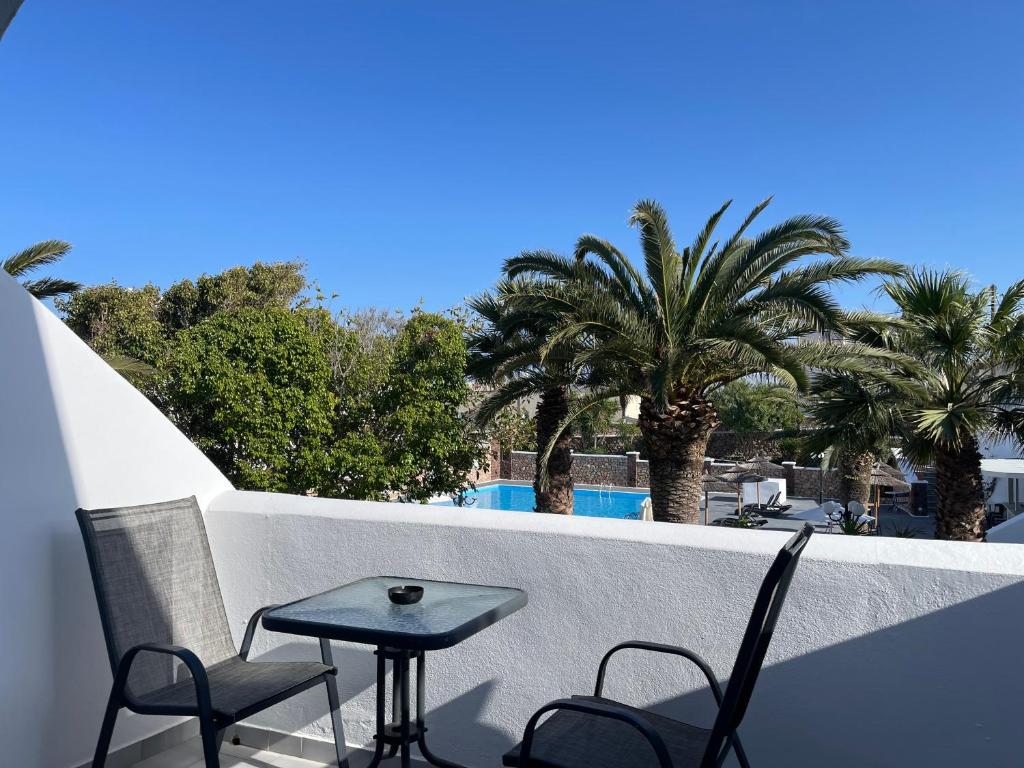 a table and chairs on a balcony with palm trees at Albatros Hotel in Karterados