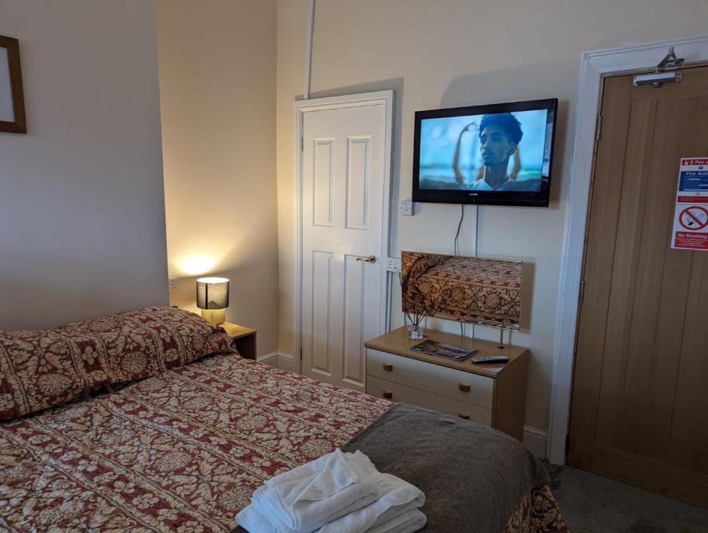 スランディドノにあるOverton Villa Hotelのベッド1台、薄型テレビが備わるホテルルームです。