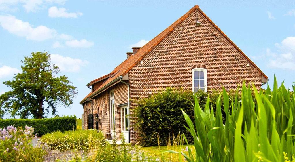an old brick house in a field with plants at Vakantiehoeve Amadee in Zonnebeke