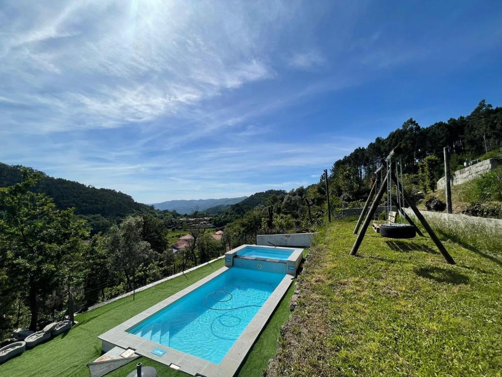 a swimming pool in a field with a swing at Casa d'Avó Lina - Gerês in Terras de Bouro