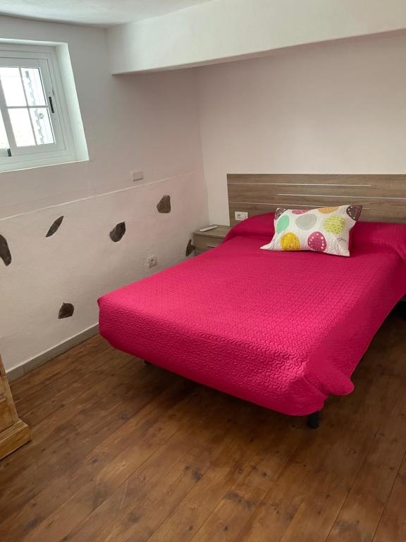 a bed with a pink comforter in a room at Vivienda Vacacional El Pajar in Breña Alta