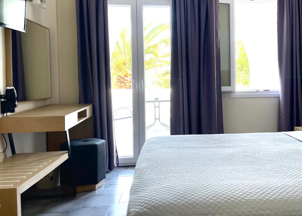 a bedroom with a bed and a desk and windows at Albatros Hotel in Karterados