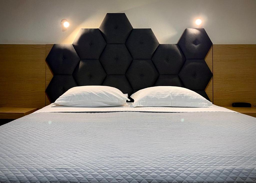 a large bed with a black headboard and two pillows at Albatros Hotel in Karterados