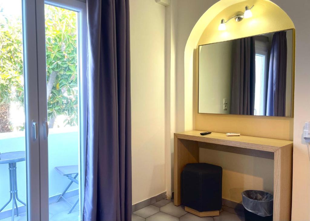 a bathroom with a vanity with a mirror and a window at Albatros Hotel in Karterados