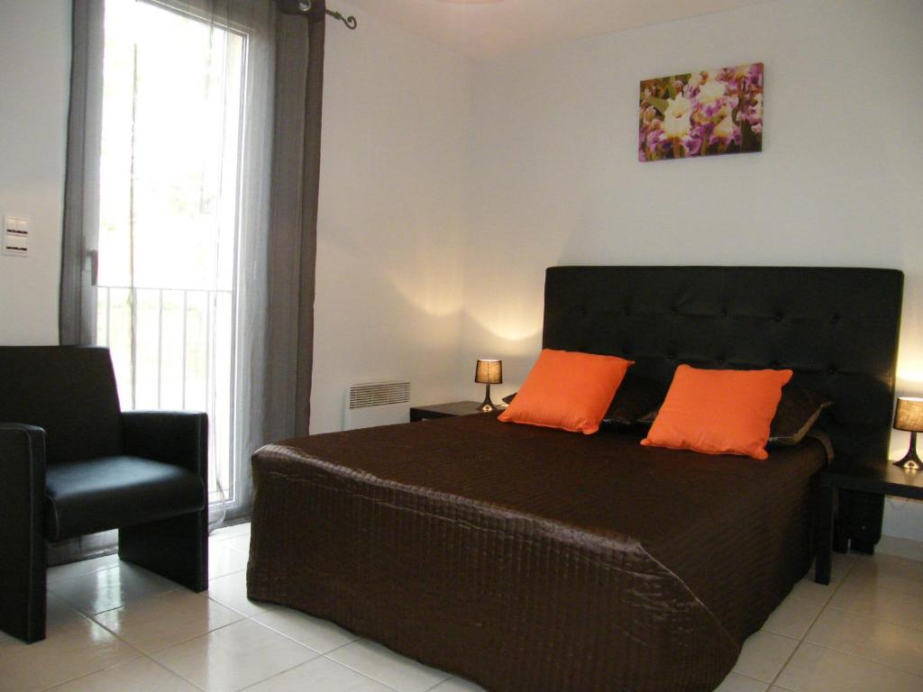 - une chambre avec un lit doté d'oreillers orange et d'une chaise dans l'établissement 64m2 soleil catalan 2km mer ok chéques vacances 2ch 4 pers, à Latour-Bas-Elne