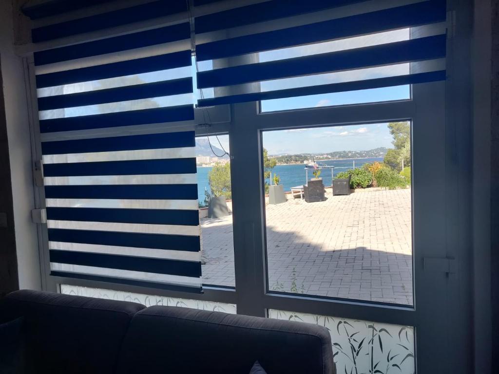 ein Fenster mit einer blau-weiß gestreiften Jalousie in der Unterkunft Appartement Le Rescator à Tamaris vue mer exceptionnelle climatisé résidence avec piscine et parking in La Seyne-sur-Mer