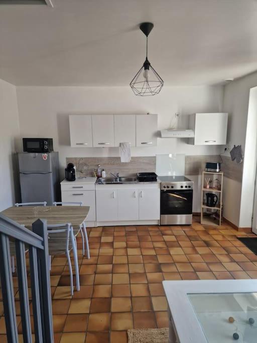 une cuisine avec des armoires blanches et un plancher en bois dans l'établissement Maison de ville, à Doudeville