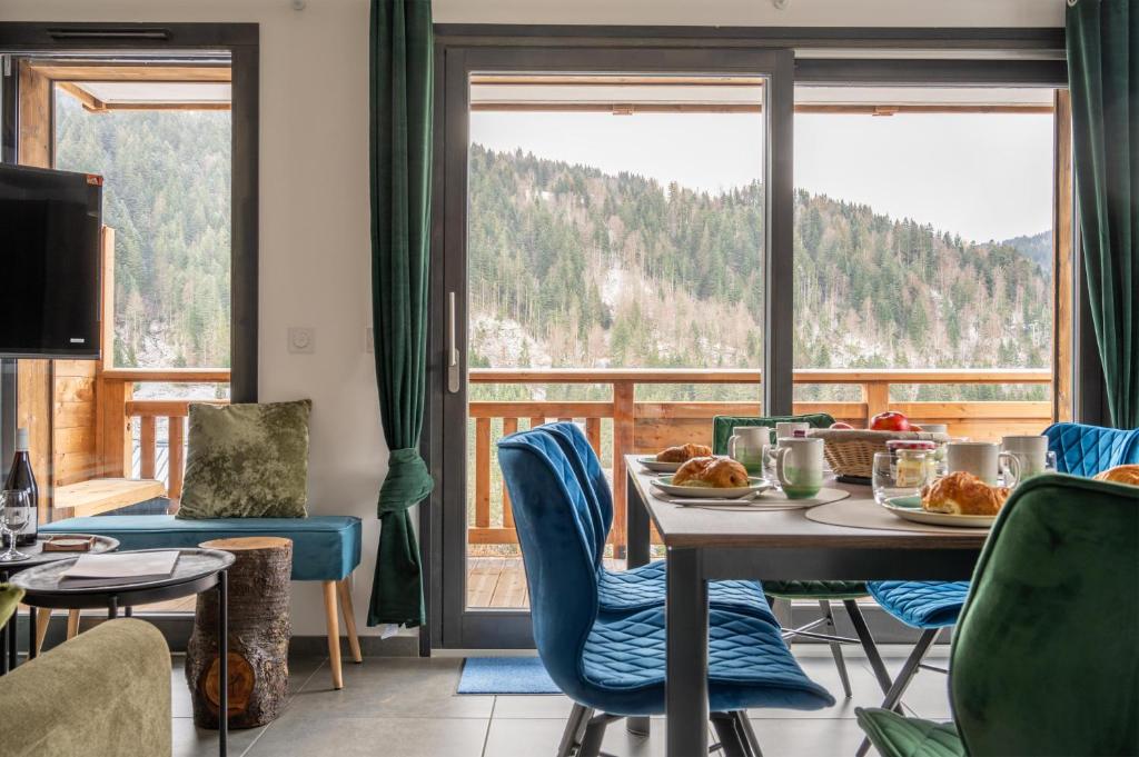 une salle à manger avec une table et des chaises et une grande fenêtre dans l'établissement Hameau des Cornuts - Apartment B01, aux Gets
