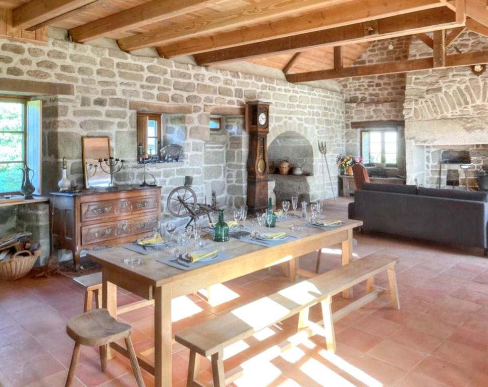 ein Esszimmer mit einem Tisch und einer Steinmauer in der Unterkunft Maison de 2 chambres avec jardin amenage et wifi a Chaumeil in Chaumeil