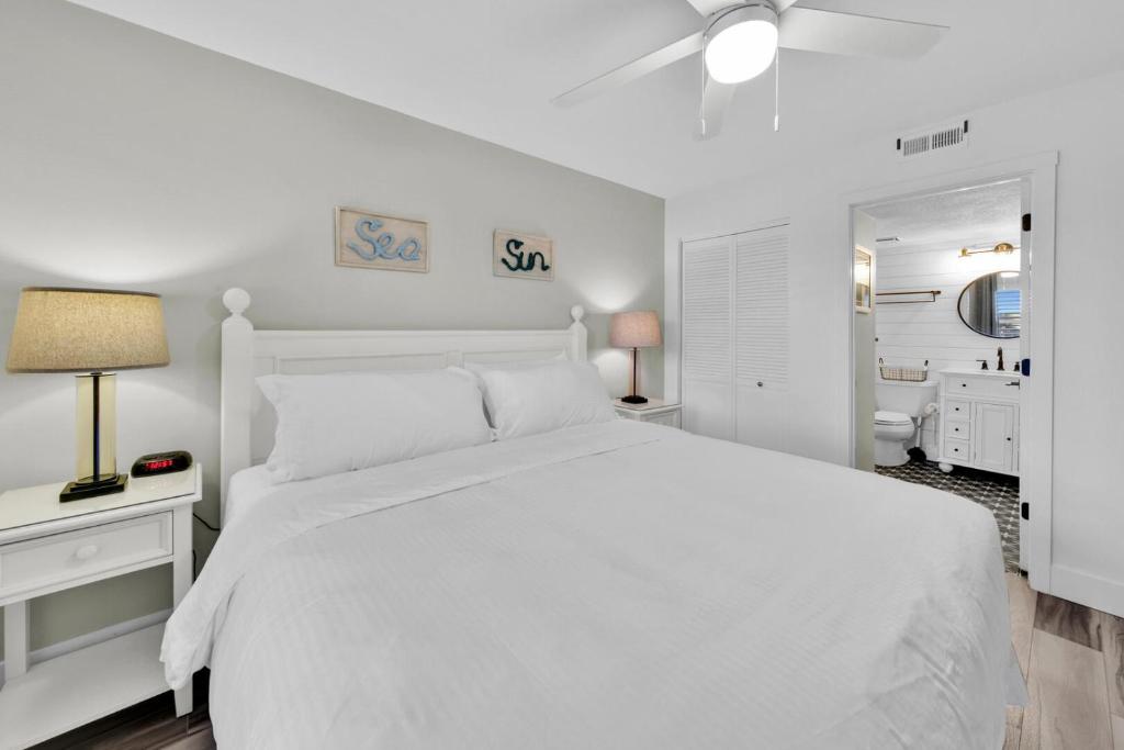ein weißes Schlafzimmer mit einem weißen Bett und einem Badezimmer in der Unterkunft Beautiful Updated Pelican Beach Unit!!! in Destin
