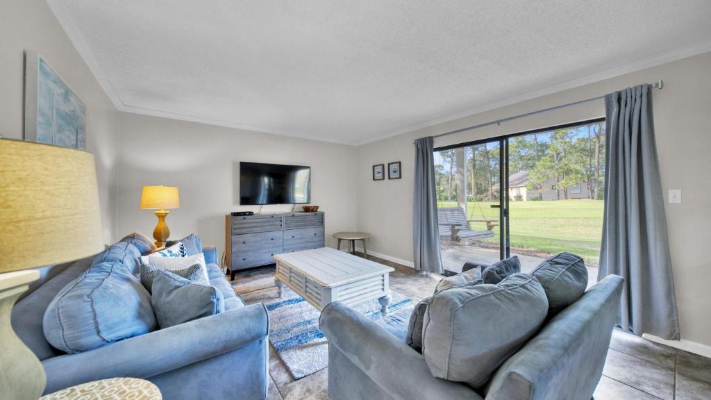 ein Wohnzimmer mit zwei blauen Sofas und einem großen Fenster in der Unterkunft Cozy renovated ground floor unit - Golf Villa - on the Golf Course in Destin