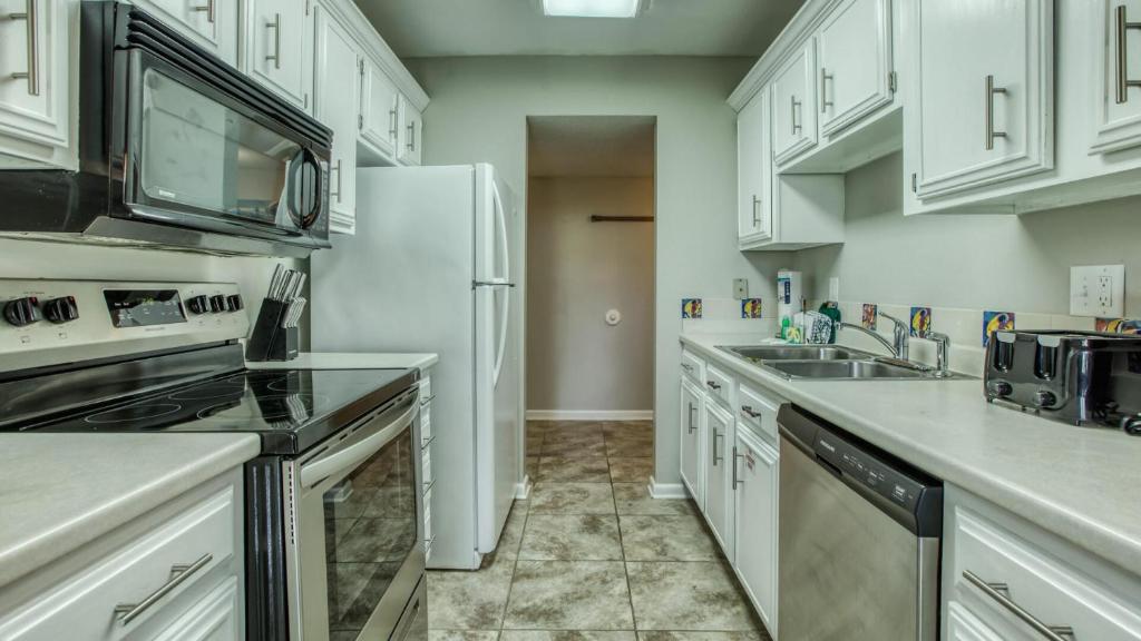 eine Küche mit weißen Schränken und einem weißen Kühlschrank in der Unterkunft Cozy renovated ground floor unit - Golf Villa - on the Golf Course in Destin