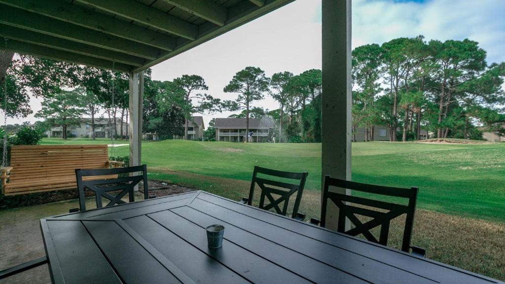 einen Tisch und Stühle auf einer Veranda mit Blick auf ein Feld in der Unterkunft Cozy renovated ground floor unit - Golf Villa - on the Golf Course in Destin