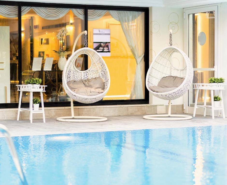 two white chairs sitting next to a swimming pool at Hotel Feldberg in Riccione