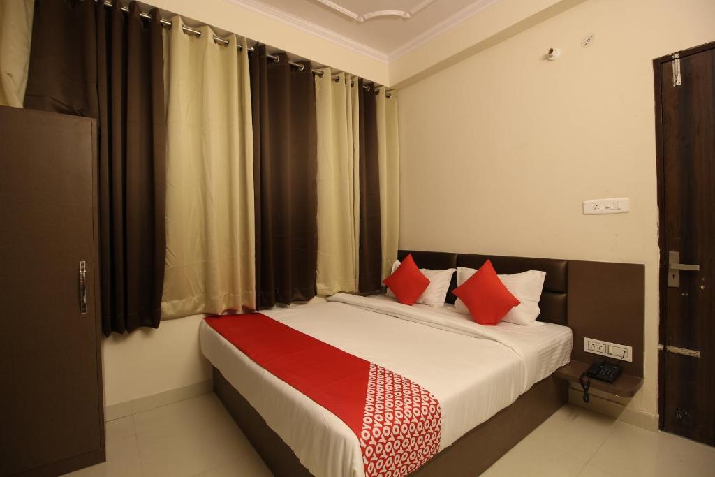 1 dormitorio con 1 cama con almohadas rojas en Super OYO Flagship Hotel Affy, en Jaipur