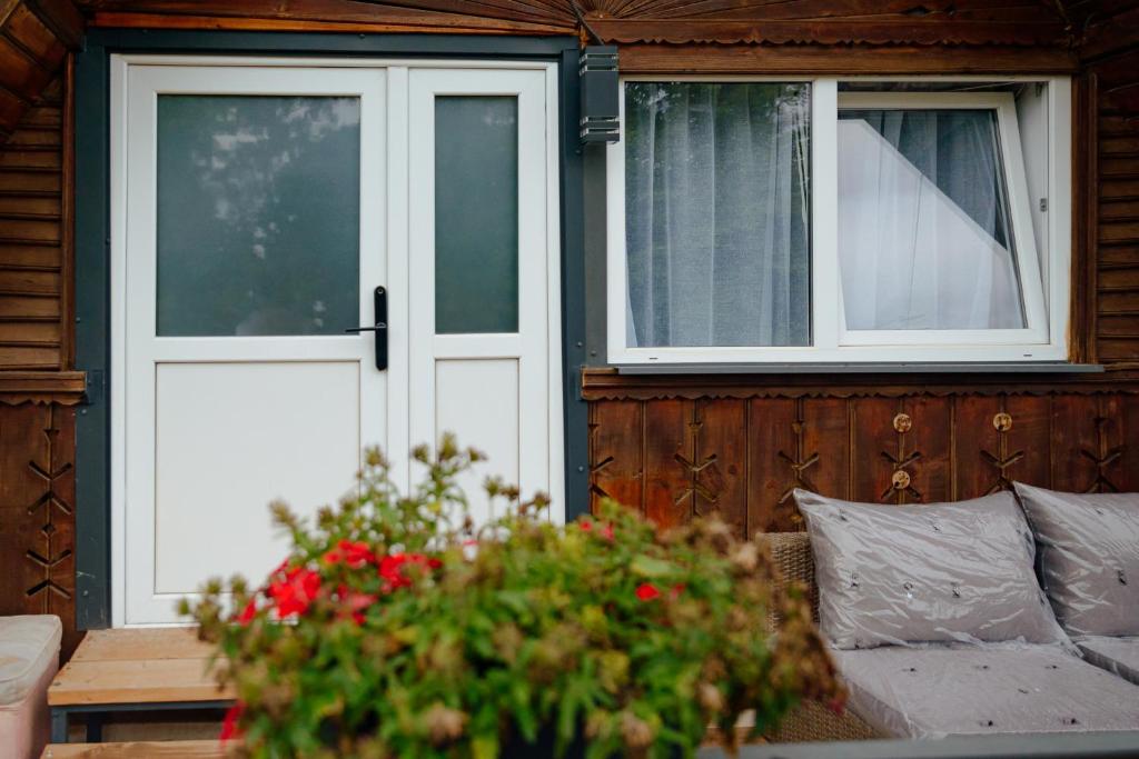 a house with a white door and a couch and flowers at Casa Gherman Cheia in Cheia