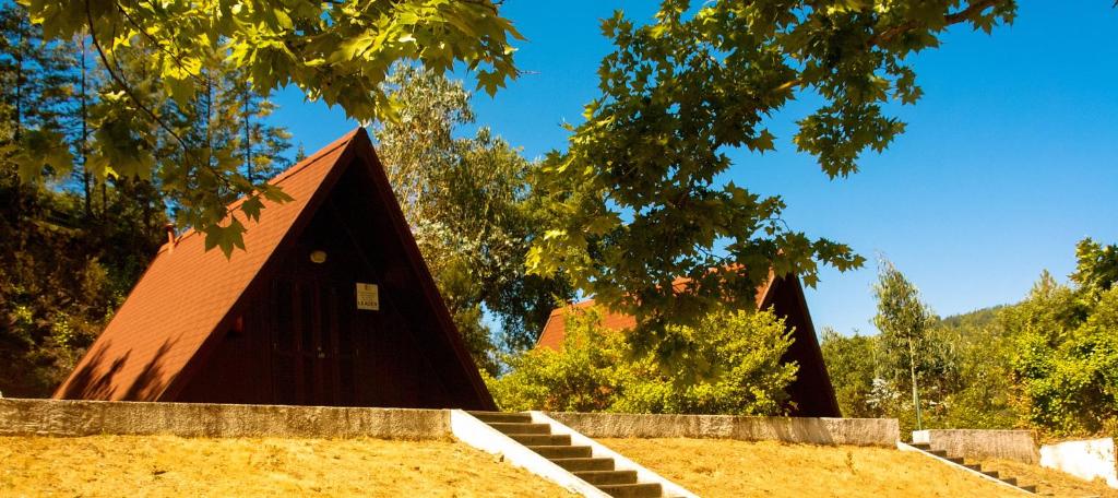 una casa marrón con escaleras en un campo con árboles en Góis Camping, en Góis