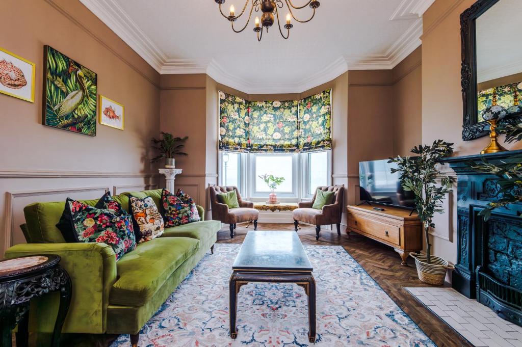 a living room with a green couch and a tv at Russell Court by Orenda-Luxe in Llandudno