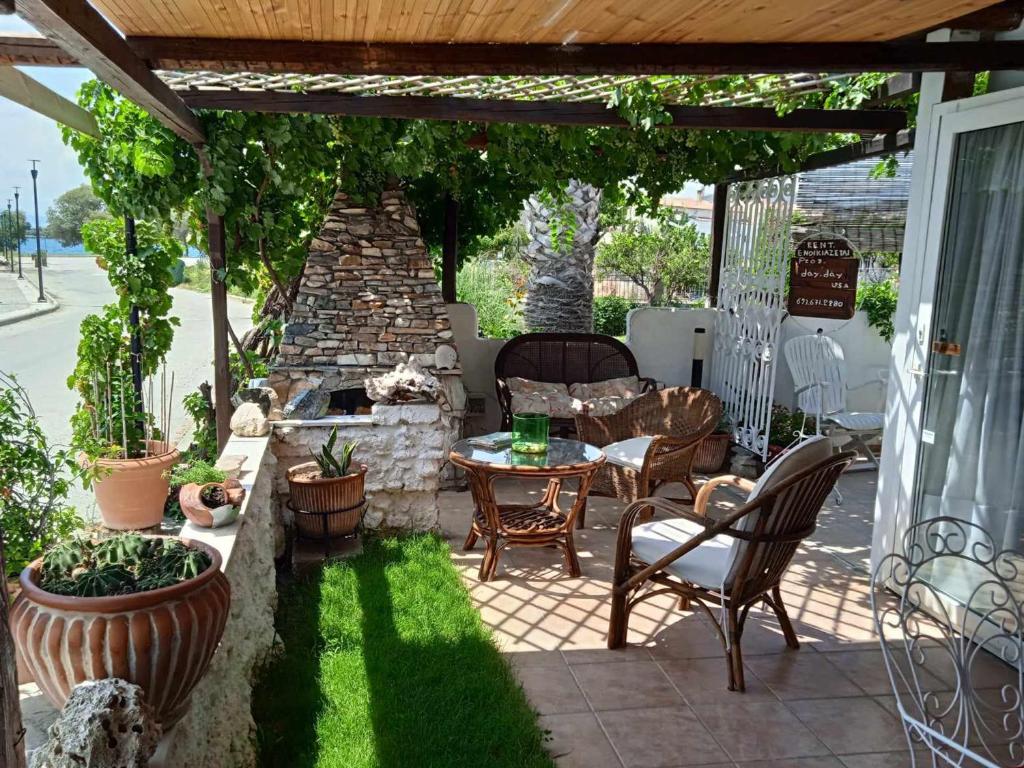 eine Terrasse mit einem Tisch und Stühlen sowie einem Steinkamin in der Unterkunft Alonaki Seafront Cottage in Nea Anchialos