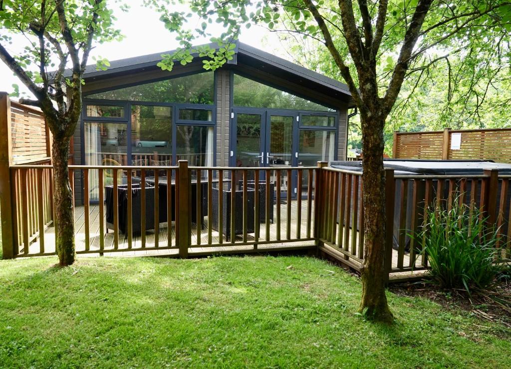 a wooden fence in front of a house with a gazebo at Spacious Oak Cabin with Hot Tub - Devon in Chudleigh