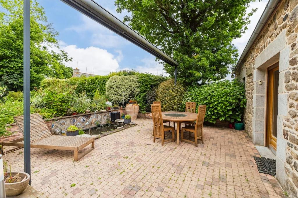 a patio with a table and chairs and a bench at Chez Papitou - Escapade Familiale en Bretagne in Saint-Adrien