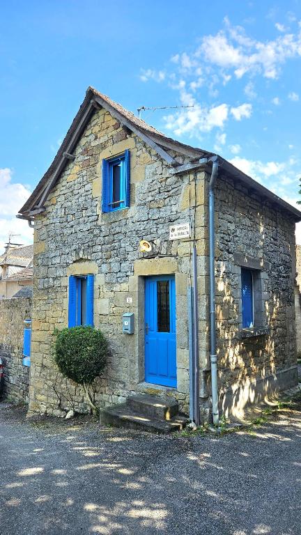 - un bâtiment en pierre avec une porte et des fenêtres bleues dans l'établissement La petite maison bleue, à Mouret