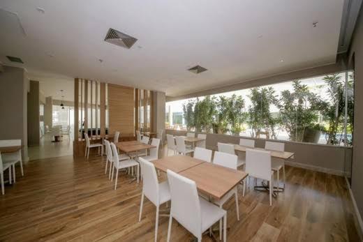 a dining room with tables and white chairs at Apartamento Neolink Barra da Tijuca in Rio de Janeiro