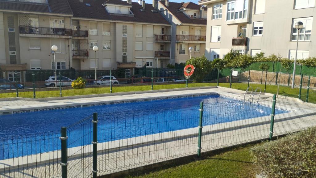 a swimming pool behind a fence with buildings in the background at Apartment Aire del Mar in Liencres