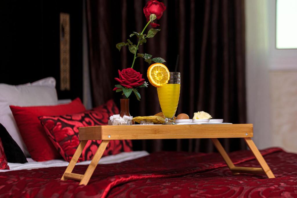 a table with a vase and a drink on a bed at Hotel Vents Des Iles in Essaouira