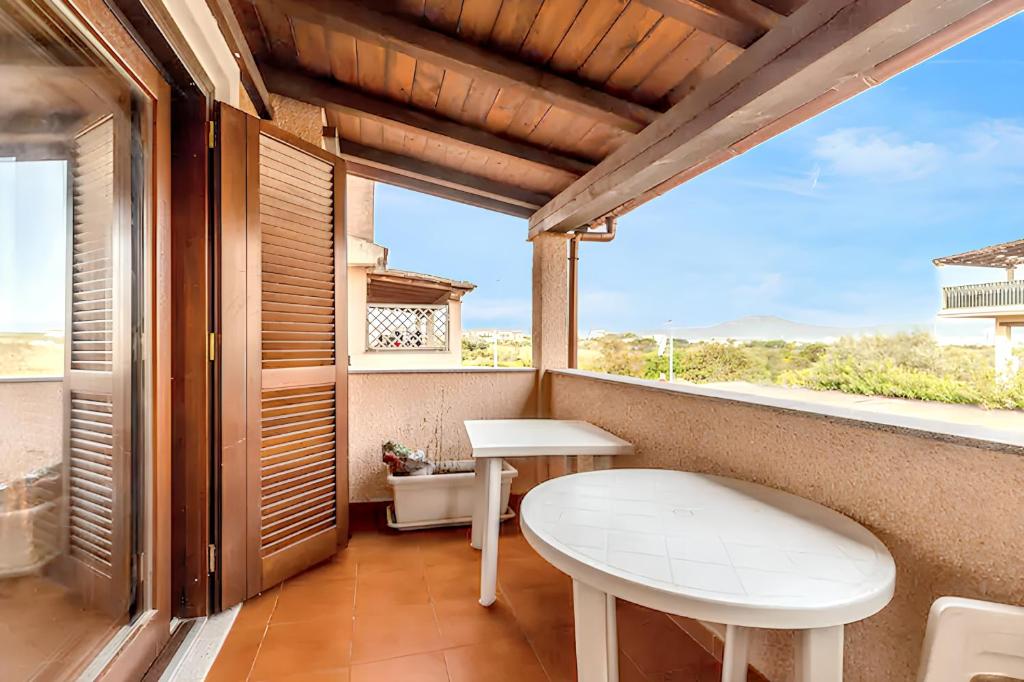 een balkon met een witte tafel en een raam bij 2 bedrooms apartement with sea view furnished terrace and wifi at Olbia 5 km away from the beach in Olbia