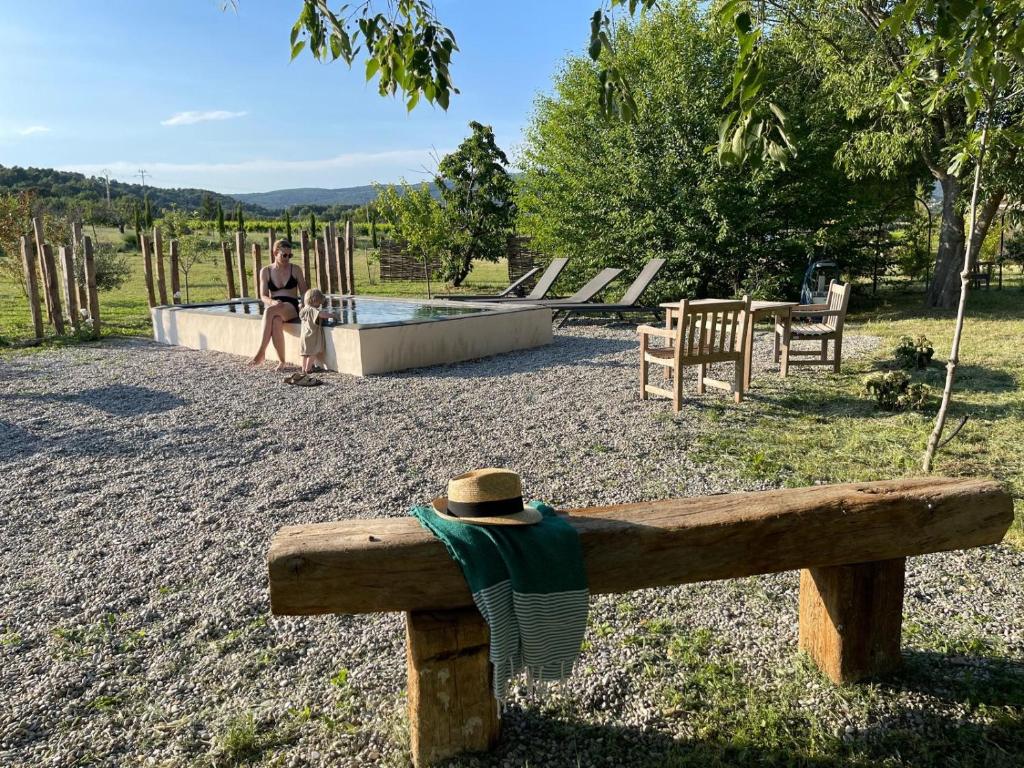 une femme assise sur un banc à côté d'une piscine dans l'établissement Domaine Saint Jean, à Saint-Saturnin-lès-Apt