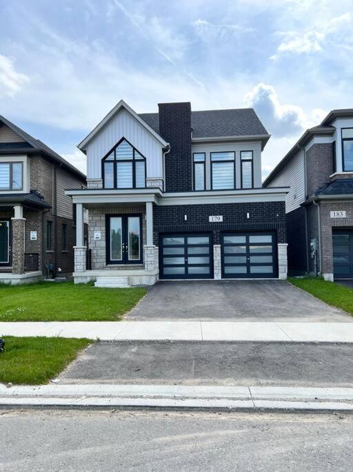 a large house with two garage doors on a street at Brand New 4 bedroom Villa by Hamilton Airport! in Hamilton