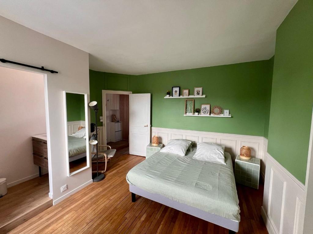 une chambre verte avec un lit et un miroir dans l'établissement Le Verde, à Melun
