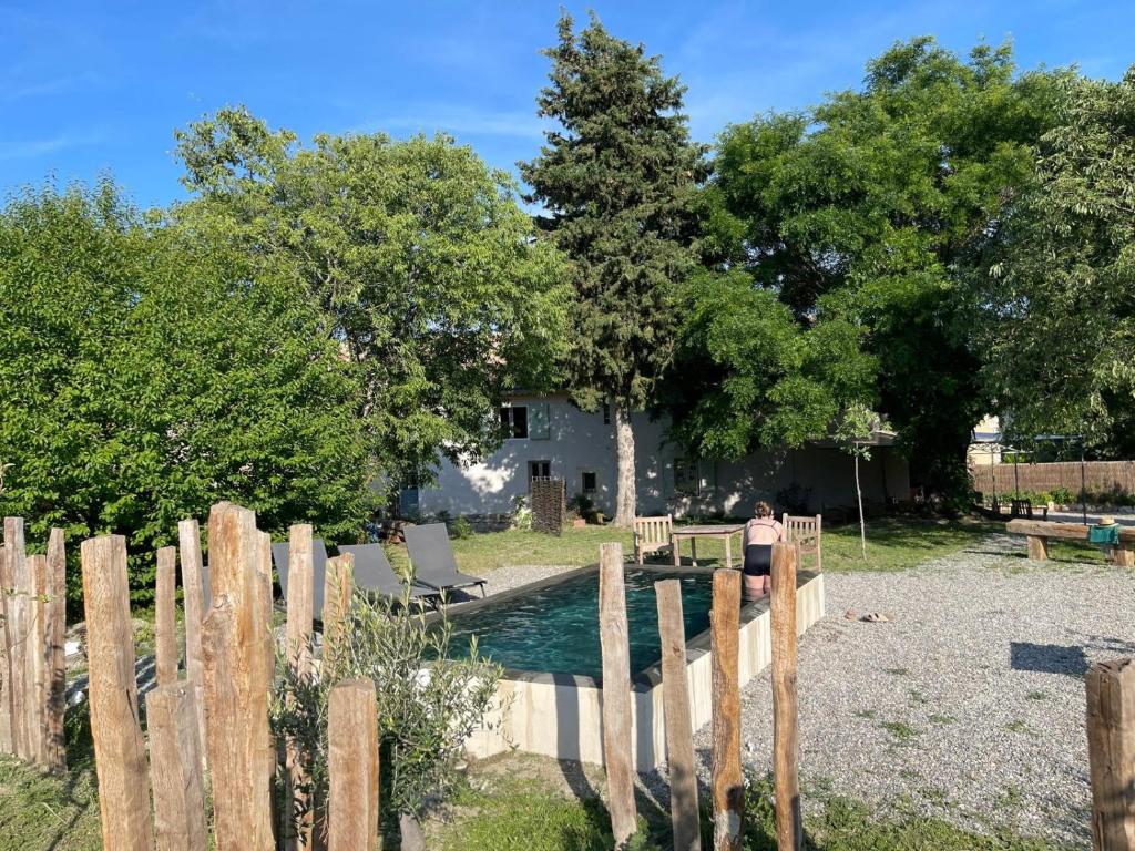 une femme marchant le long d'une clôture en bois à côté d'une maison dans l'établissement Le Domaine Saint Jean, à Saint-Saturnin-lès-Apt