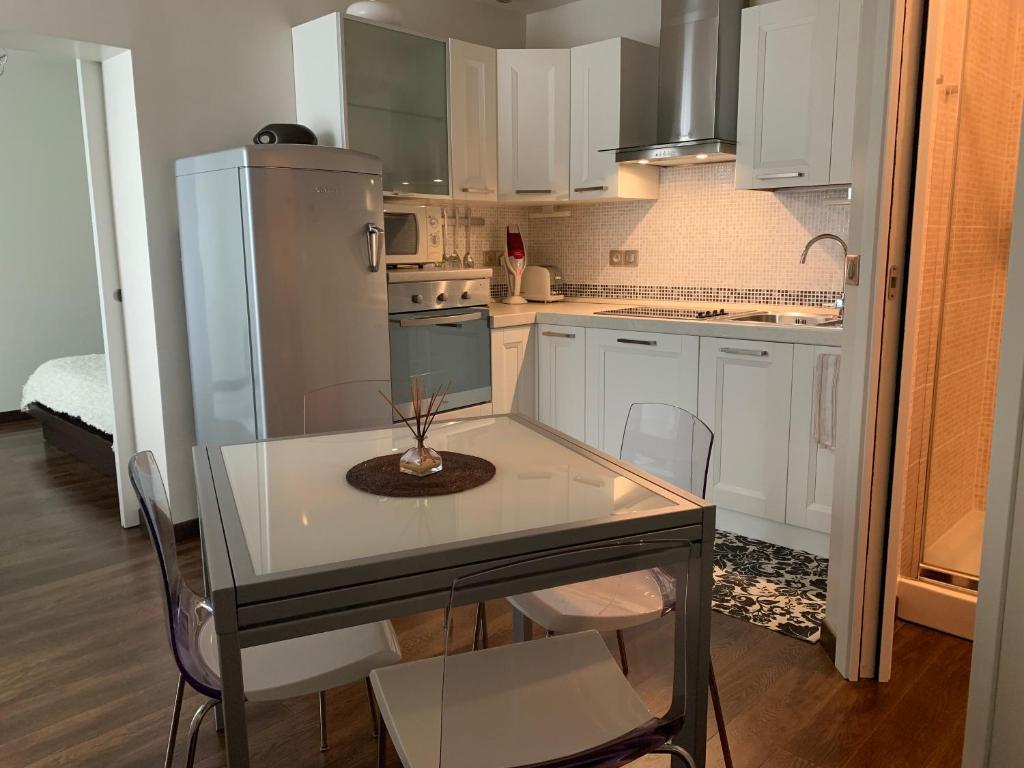 une cuisine avec des armoires blanches et une table et des chaises dans l'établissement Un nido a Versailles, à Versailles