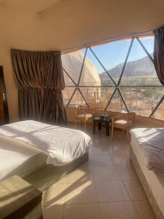 een slaapkamer met twee bedden en een groot raam bij Wadi Rum Desert Bedouins in Wadi Rum