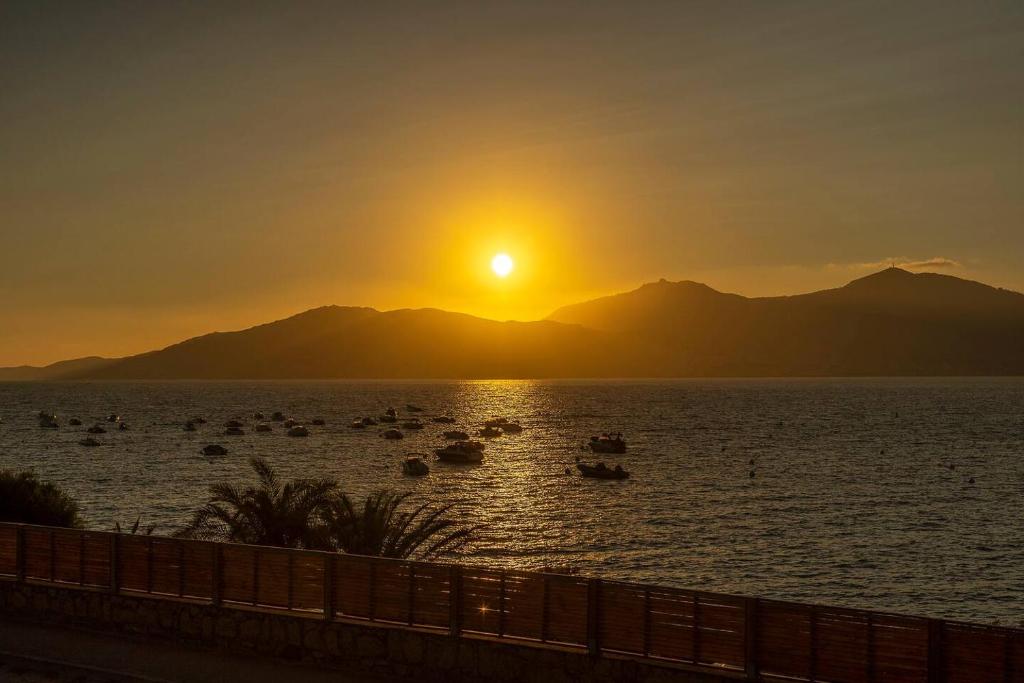 a sunset over a body of water with boats at Résidence CasaBianca Porticcio - Roccapina in Porticcio