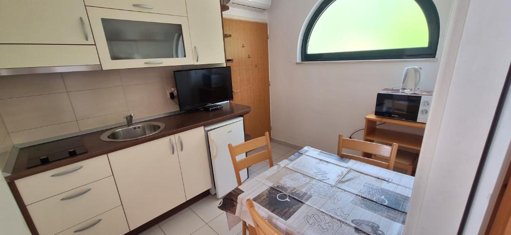 a small kitchen with a table and a sink at Apartmani Grubiša in Drvenik