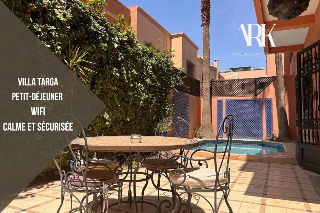 a table and chairs sitting next to a pool at Villa Targa Piscine 10 minutes du centre - ARK Realty in Marrakech