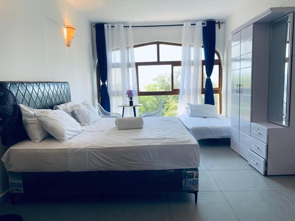 1 dormitorio con 2 camas, cortinas azules y ventana en Villa Julia, en Ukunda